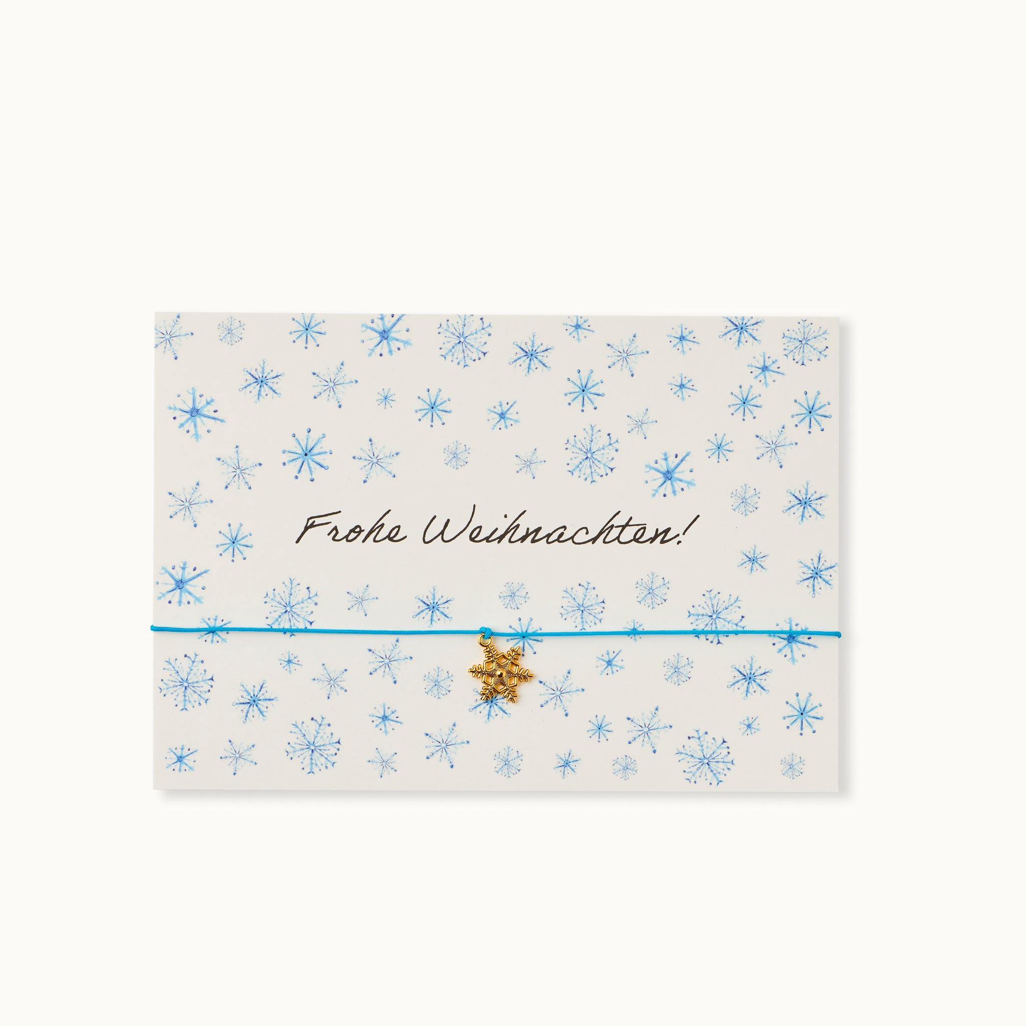 Frohe Weihnachten! Karte mit einer Schneeflocke als 18K vergoldeter Anhänger an einem blauen Armband.